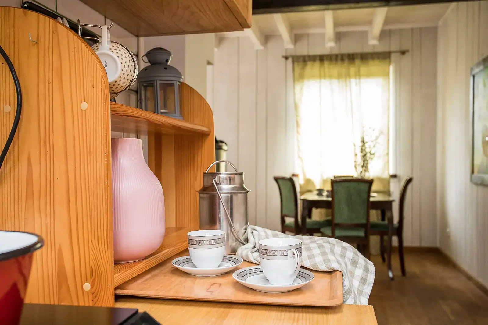 Kuchnia w apartamencie: kredens z filiżankami, w głębi jadalnia